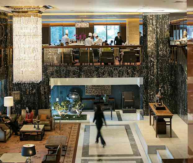 Hotellobby med elegante møbler, store vinduer og en stor krystallkrone som henger fra taket. (AI-generert tekst)