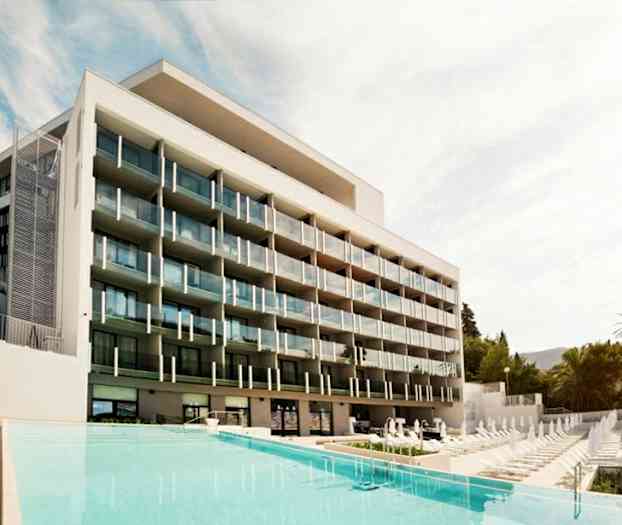 Et moderne hotell med flere balkonger foran et basseng. (AI-generert tekst)