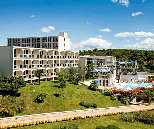 En bygning med omgivelser av en velstelt plen og hage, med et svømmebasseng og uteserveringer. (AI-generert tekst)