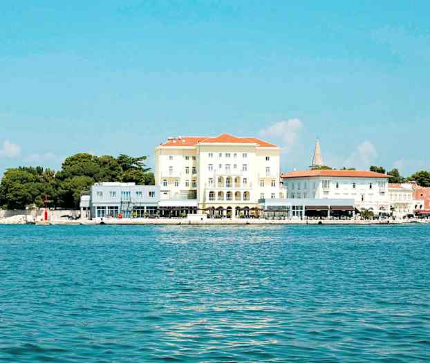 Bilde av en bygning ved kysten med blått hav og klar himmel. (AI-generert tekst)