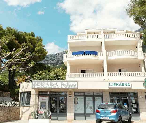 Bygning med balkonger og butikker i første etasje. (AI-generert tekst)