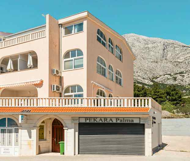 En bygning med flere etasjer og balkonger. Den nedre delen har skilt for forretningsvirksomhet. (AI-generert tekst)