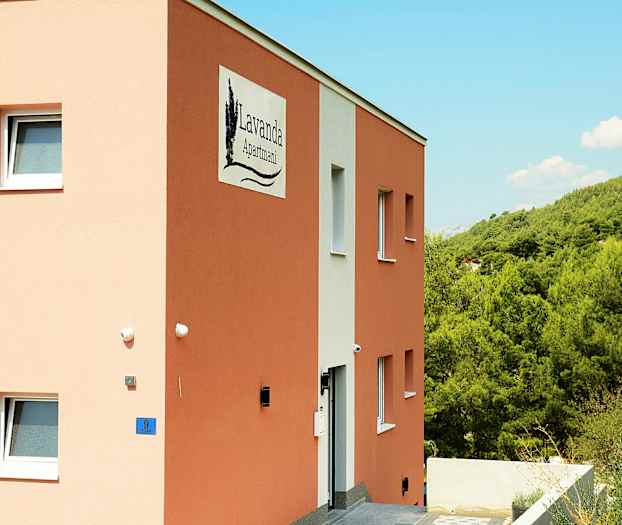Illustrasjon av en bygning med skiltet 'Lavanda Apartmani', omgitt av grønn vegetasjon. (AI-generert tekst)