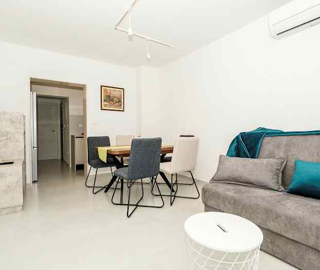 Et moderne oppholdsrom med grå sofa, spisebord og stoler. (AI-generert tekst)