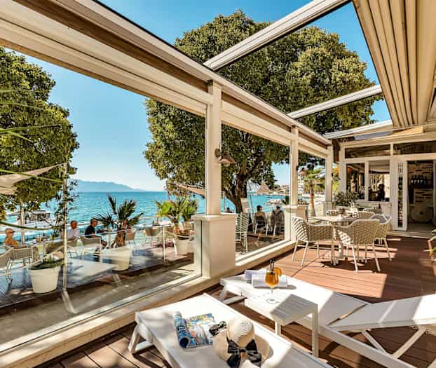 En terrasse med sitteplasser, solsenger og utsikt over havet. (AI-generert tekst)