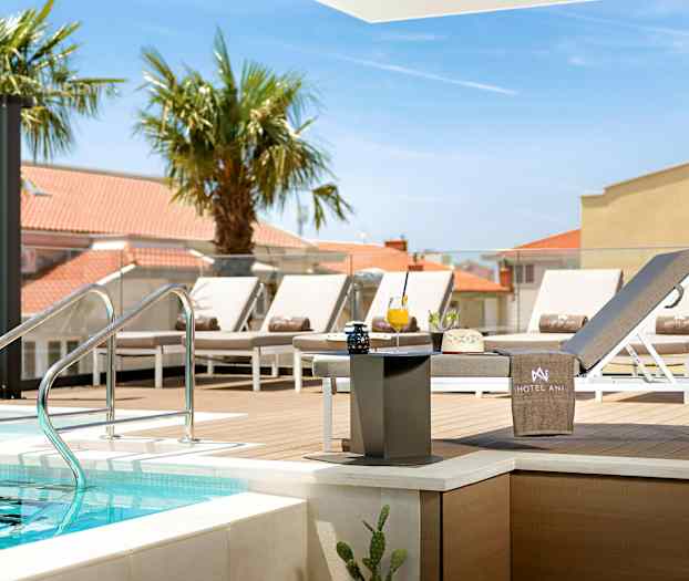 Bassengområde med solsenger og bord nær en treplattform. (AI-generert tekst)