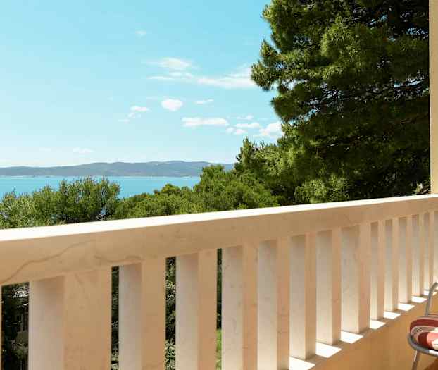 En balkong med utsikt over havet og trær. (AI-generert tekst)