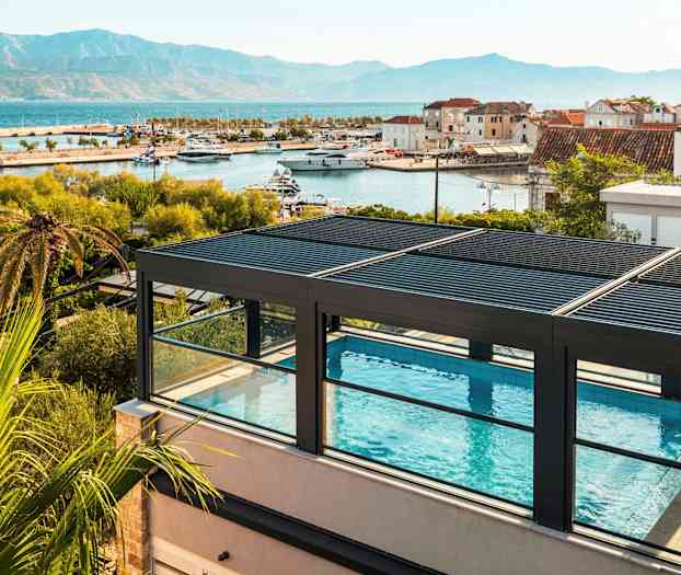 Takbasseng med utsikt over havn og fjell. (AI-generert tekst)