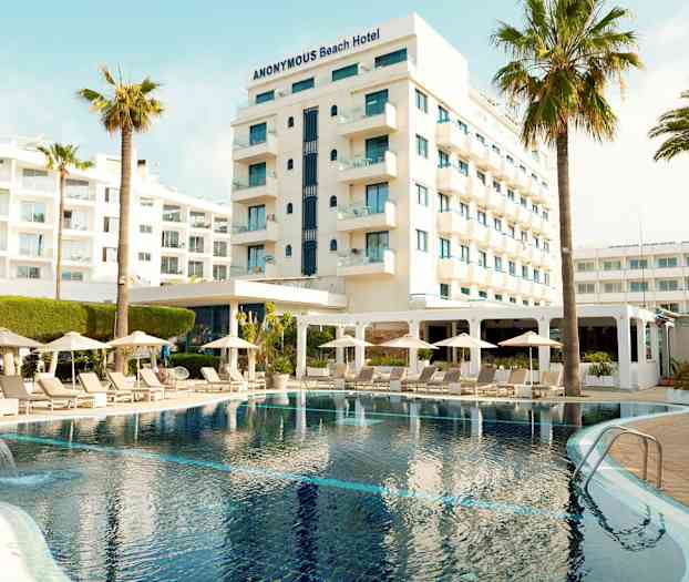 Hotell med basseng, solsenger og parasoller i forgrunnen. (AI-generert tekst)