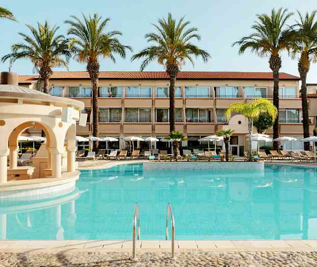 Bilde av et hotell med utendørsbasseng og omkringliggende solsenger og parasoller. (AI-generert tekst)