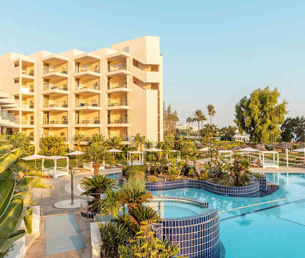 Hotellbygning med balkonger, bassengområde og grøntområder. (AI-generert tekst)