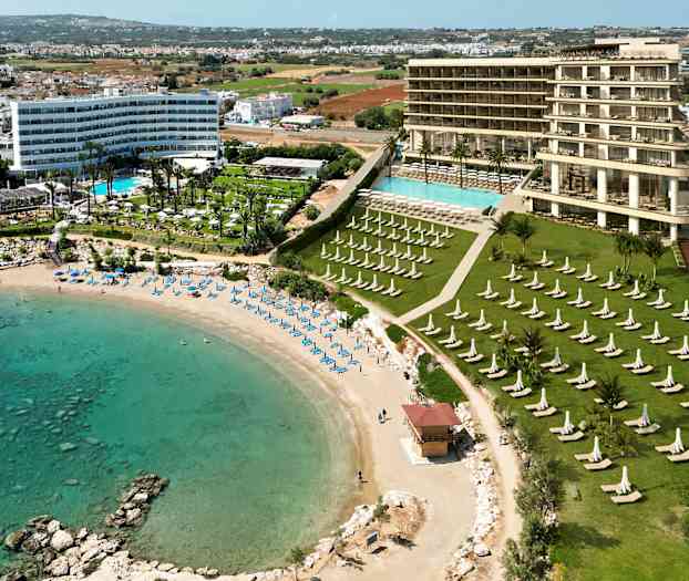 Utsikt over et hotell med bassengområde nær en sandstrand og turkist vann. (AI-generert tekst)