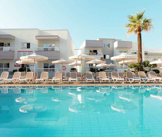 Bilde av et basseng med solsenger og parasoller foran et hotell. (AI-generert tekst)