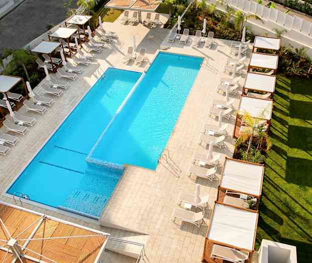 Utsikt over et utendørs basseng omgitt av solstoler og skyggegivende pergolaer. (AI-generert tekst)