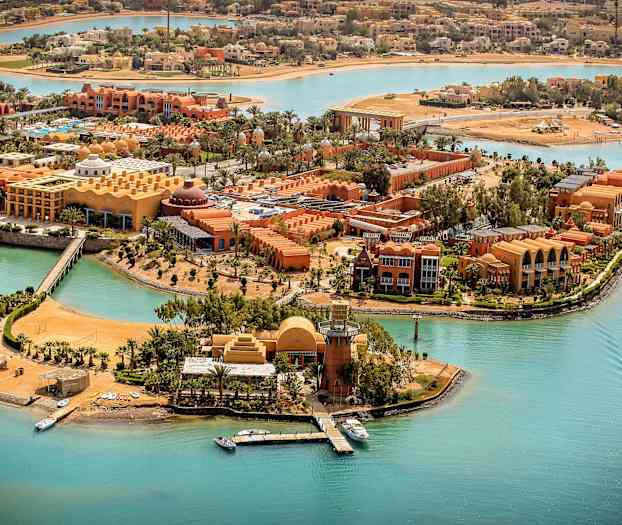 Luftfoto av en resort ved turkise kanaler med båter og palmetrær. (AI-generert tekst)