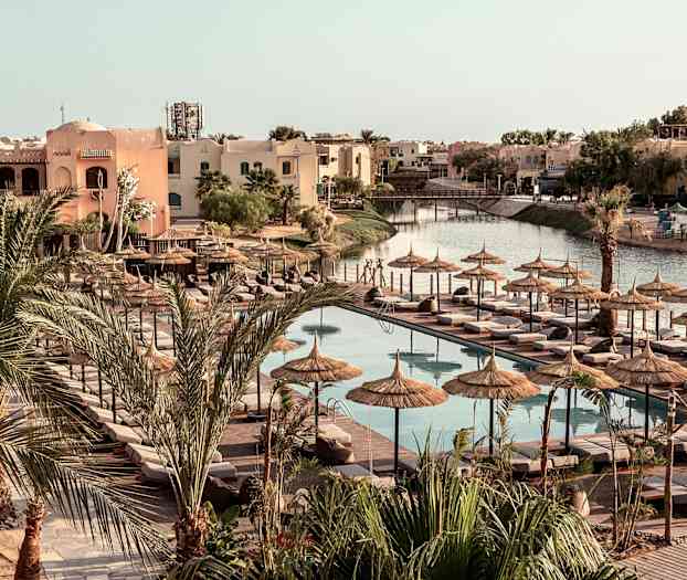 Bassengområde med solsenger og parasoller, omgitt av palmer og bygninger. (AI-generert tekst)