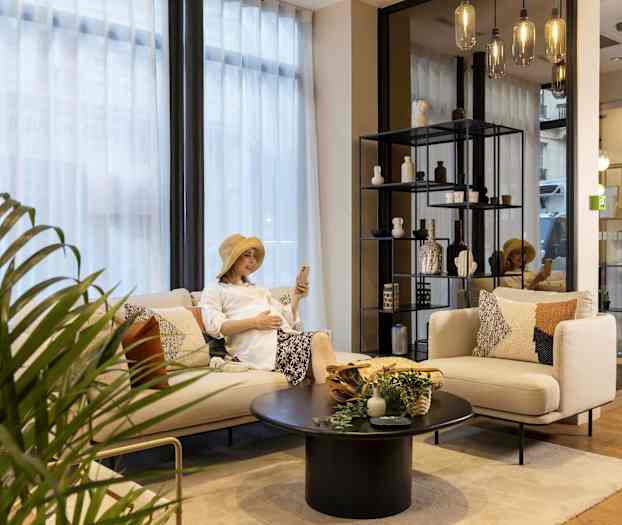 Salong med sofa, bord og hylle med dekorasjoner, samt en plante og glasslamper. (AI-generert tekst)