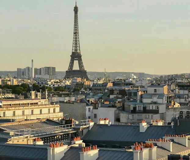 Eiffeltårnet i Paris med omkringliggende bygninger i forgrunnen. (AI-generert tekst)