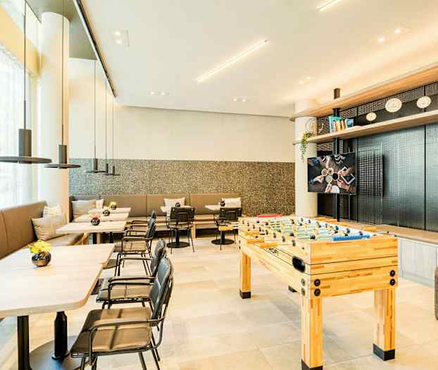 Et moderne rom med bord, stoler og et bordfotballspill. (AI-generert tekst)