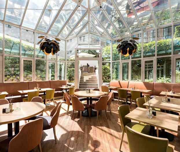 Lukket restaurant med glassvegger, sitteplasser og belysning. (AI-generert tekst)