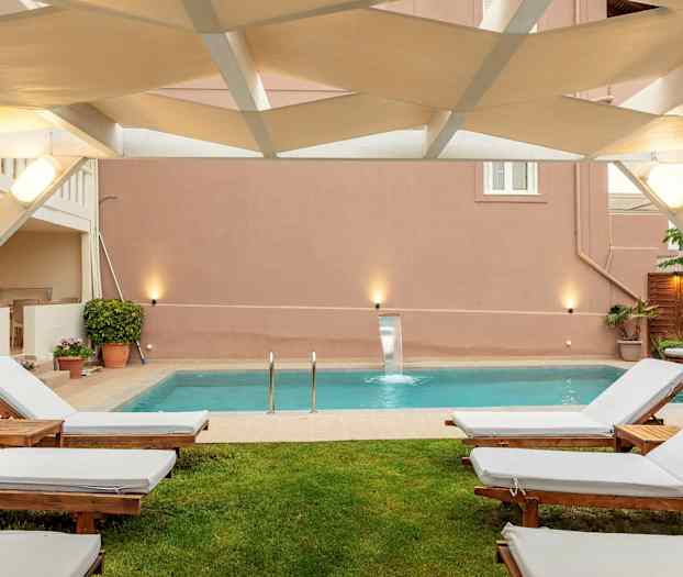 Utendørs sitteområde med solsenger og et basseng. (AI-generert tekst)