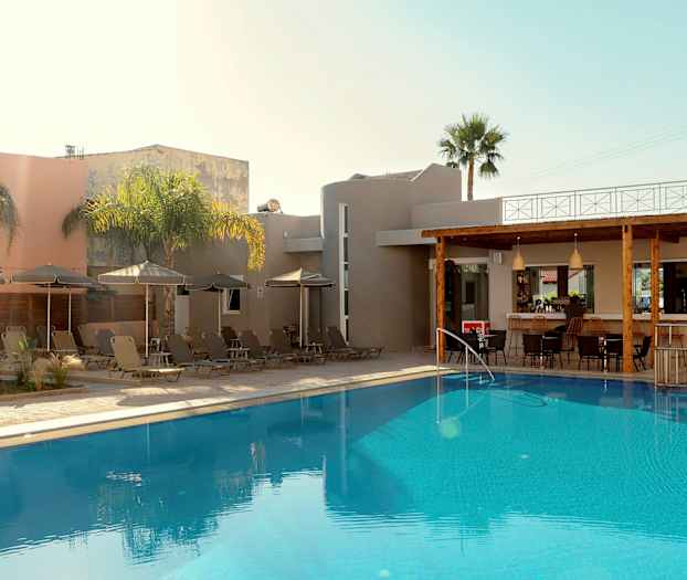 Et utendørs svømmebasseng ved en bygning med solsenger og parasoller samt en bar. (AI-generert tekst)