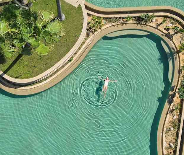 En person flyter i et basseng med grønn omgivelse. (AI-generert tekst)