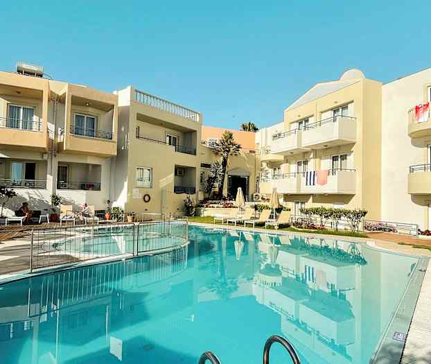 Eksteriør av en bygning med balkonger og et basseng i forgrunnen. (AI-generert tekst)