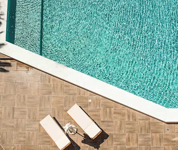 To solsenger på en trebjelk ved siden av et svømmebasseng. (AI-generert tekst)