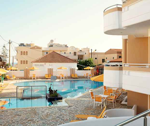 Et svømmebasseng med solsenger og parasoller ved et hotell. (AI-generert tekst)