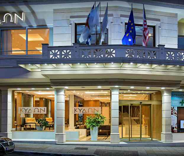 Bygningens inngang med glassdører, lyse fasadedekorasjoner og belysning som lyser opp området. (AI-generert tekst)