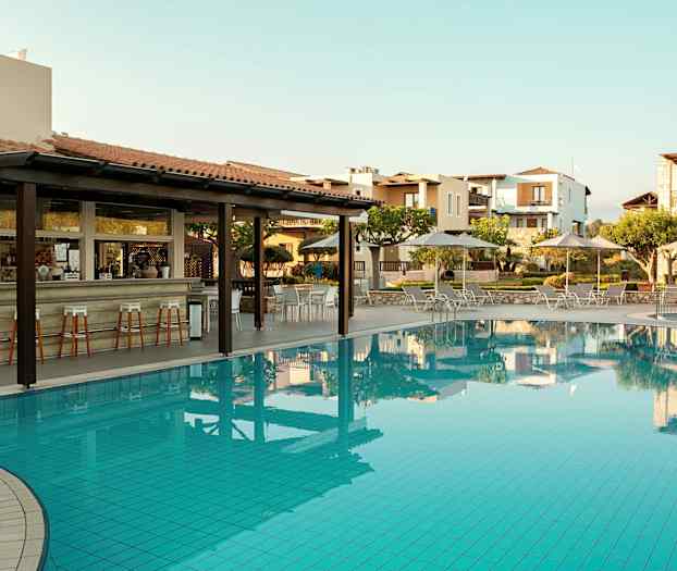 Et utendørsbasseng med solsenger og parasoller, samt en bar med høye stoler ved siden av. (AI-generert tekst)