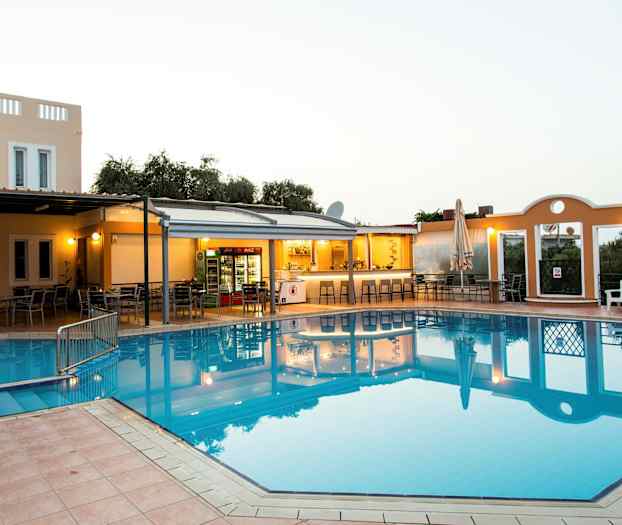 Et utendørsbasseng ved et hotell med tilhørende bar og sittegrupper. (AI-generert tekst)