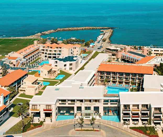 Flyfoto av et hotellkompleks ved kysten med bassenger, bygninger og havet i bakgrunnen. (AI-generert tekst)