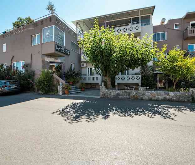 Utvendig av en bygning med boliger og parkerte biler foran. (AI-generert tekst)