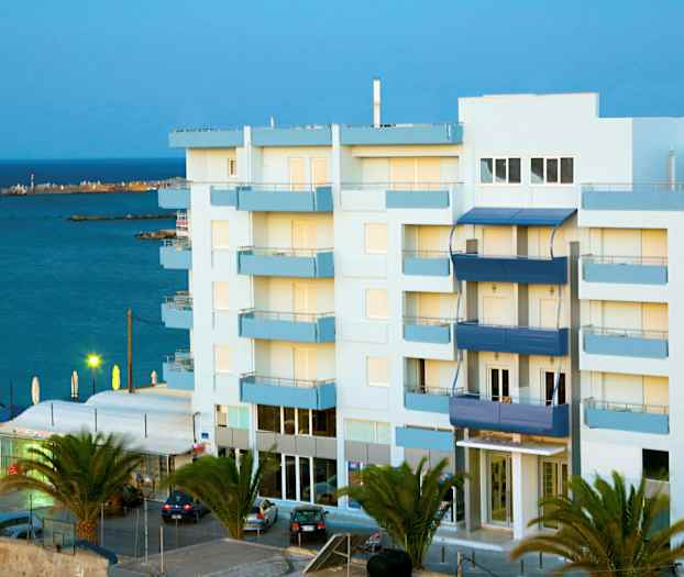 Flerfamiliehus nær sjøen, omgitt av palmer. (AI-generert tekst)