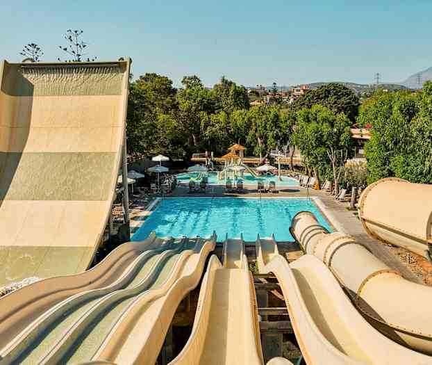 Bilde av en vannpark med flere vannsklier som går ned til et basseng omgitt av grønne trær. (AI-generert tekst)