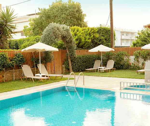 Utendørsbasseng med solsenger og parasoller samt frodig omgivelser. (AI-generert tekst)