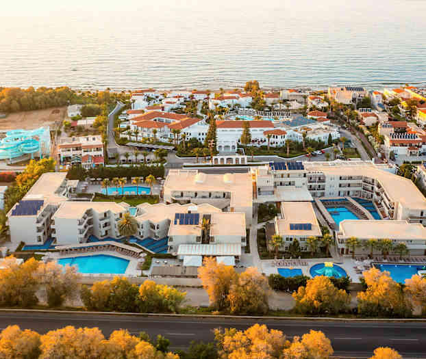 Luftfoto av et feriested med flere bassenger og vannsklier ved sjøen. (AI-generert tekst)