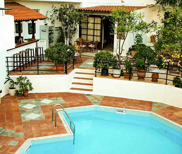 Et utendørs svømmebasseng med nærliggende spiseplass og bar, omgitt av grøntområder. (AI-generert tekst)