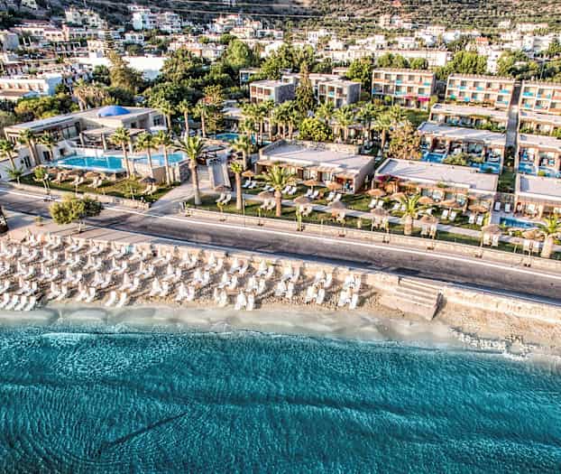 Luftfoto av et feriested ved stranden med parasoller og solsenger. (AI-generert tekst)