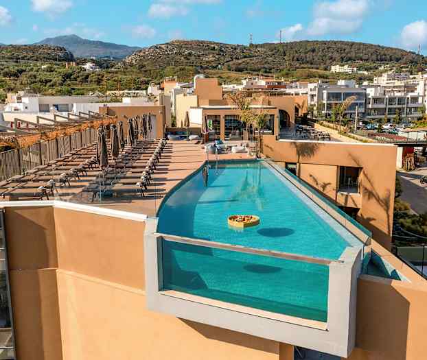 Et utendørs basseng på en takterrasse med solsenger ved siden av. (AI-generert tekst)