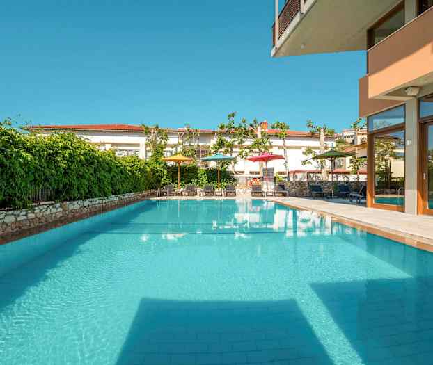 Utendørs svømmebasseng med omkringliggende grøntområder og møblerte steder. (AI-generert tekst)