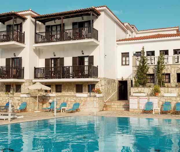 Hvit bygning med balkonger og et basseng foran. (AI-generert tekst)