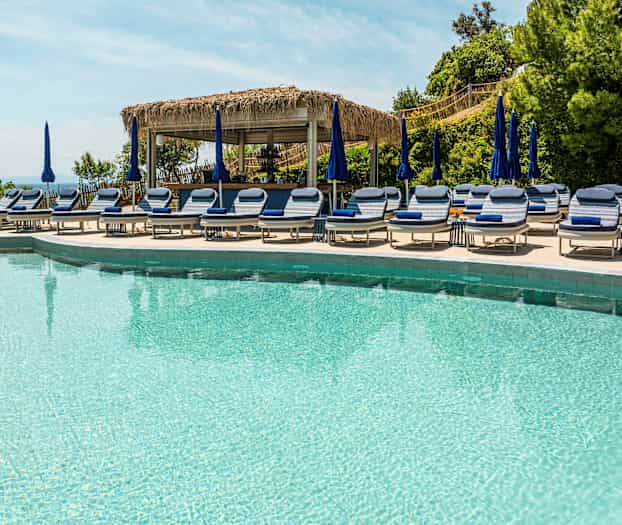 Basseng med solsenger og parasoller. (AI-generert tekst)