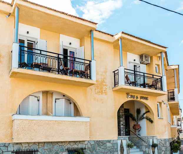 Eksteriør av en gul bygning med balkonger og en inngang. (AI-generert tekst)