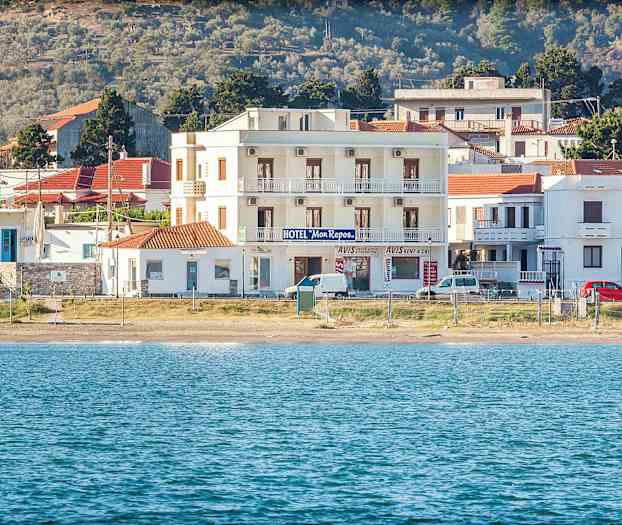 Hotellbygning ved strand med hav i forgrunnen. (AI-generert tekst)