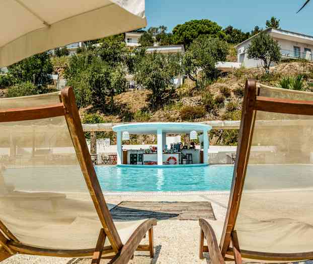 To solstoler ved kanten av et basseng med en bar i bakgrunnen. (AI-generert tekst)