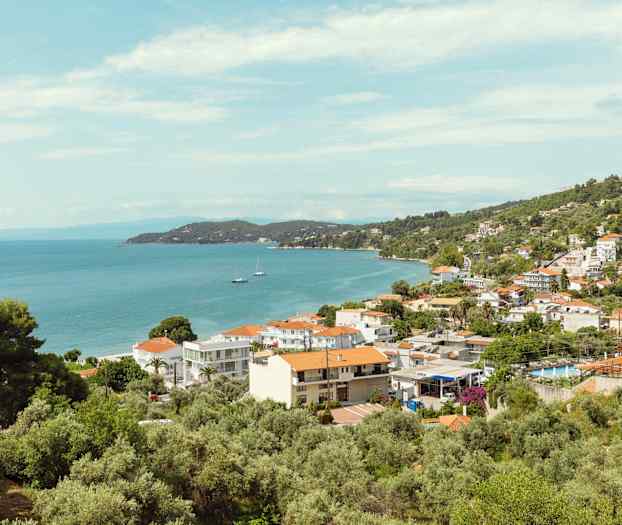 Utsikt over en kystby med hus, trær og hav. (AI-generert tekst)
