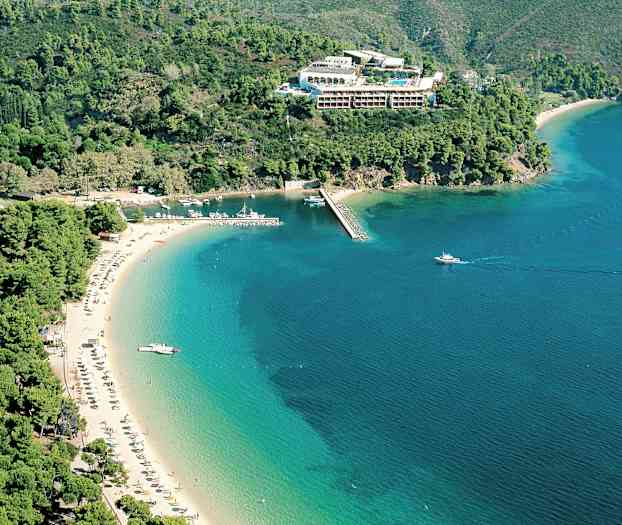 Luftfoto av stranden ved kysten, omgitt av grønne fjell og hav. (AI-generert tekst)